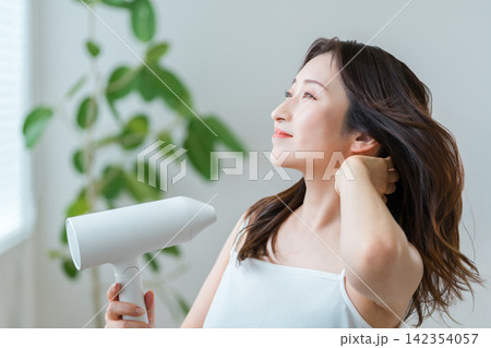 ドライヤーで髪を乾かす40代女性,ヘアケアと美髪習慣 ドライヤーで髪を乾かす40代女性,ヘアケアと美髪習慣 142354057