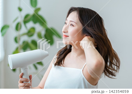 ドライヤーで髪を乾かす40代女性,ヘアケアと美髪習慣 142354059