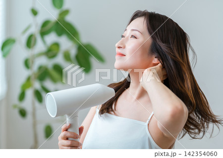 ドライヤーで髪を乾かす40代女性,ヘアケアと美髪習慣 142354060