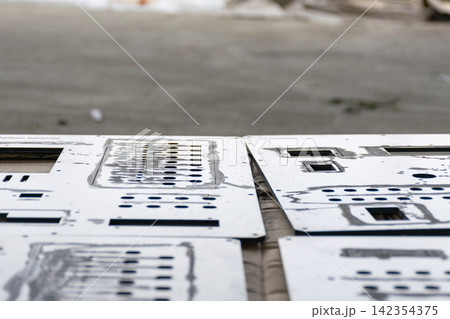 White metal panels precision cut holes openings arranged work surface for industrial fabrication manufacturing component production 142354375