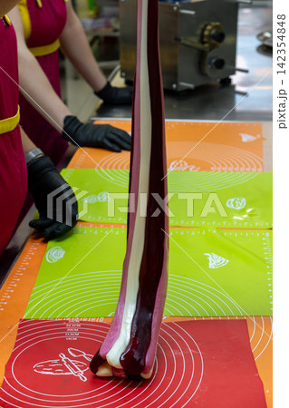 Confectioner Rolling Thick Multicolored Caramel Loaf on Silicone Table Mat Confectioner Rolling Thick Multicolored Caramel Loaf on Silicone Table Mat 142354848