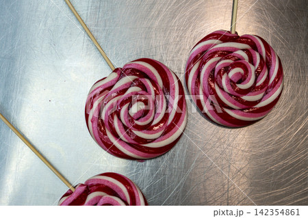 Pair of Striped Swirl Lollipops on Scratched Stainless Steel Worktop Pair of Striped Swirl Lollipops on Scratched Stainless Steel Worktop 142354861
