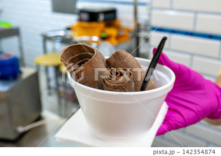 Vendor Serving Rolled Chocolate Ice Cream Dessert in White Plastic Bowl Vendor Serving Rolled Chocolate Ice Cream Dessert in White Plastic Bowl 142354874