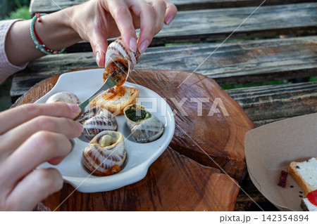 Woman Hands Extracting Cooked Escargot from Shell for Tasting Event Woman Hands Extracting Cooked Escargot from Shell for Tasting Event 142354894