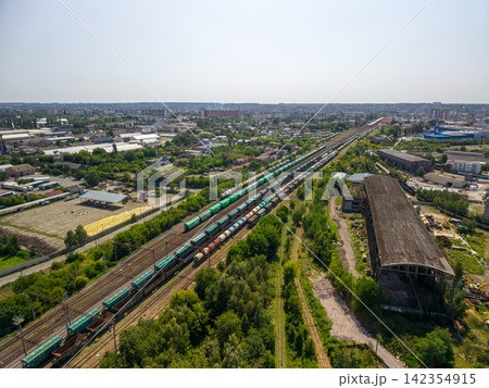 Drone view of multiple freight train lines with green and brown cargo wagons at railway yard 142354915
