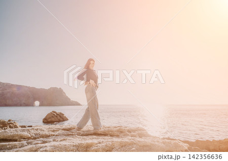 Woman coast sunset standing on rocky shore with natural arch for an adventurous travel and lifestyle concept 142356636
