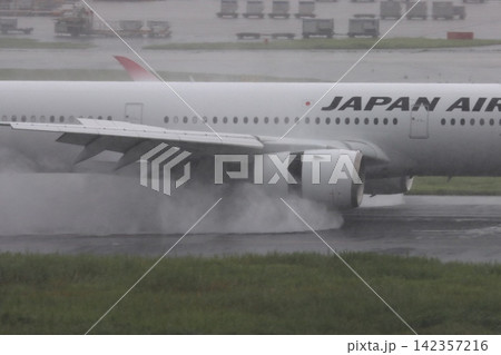 雨の滑走路に着陸する旅客機 エンジンの逆噴射の水煙 雨の滑走路に着陸する旅客機 エンジンの逆噴射の水煙 142357216