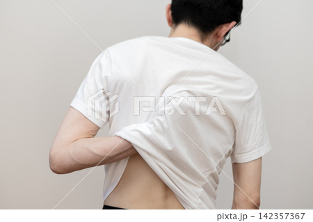 乾燥肌やあせもによる背中の痒みに悩むミドル男性の後ろ姿 乾燥肌やあせもによる背中の痒みに悩むミドル男性の後ろ姿 142357367