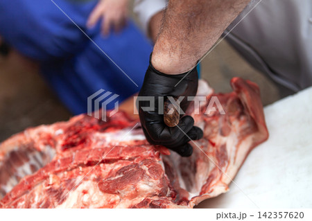 Meat cutting by the butcher and his apprentice Meat cutting by the butcher and his apprentice 142357620