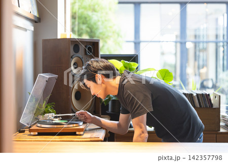 レコードプレイヤーを操作して音楽を楽しむ男性 レコードプレイヤーを操作して音楽を楽しむ男性 142357798