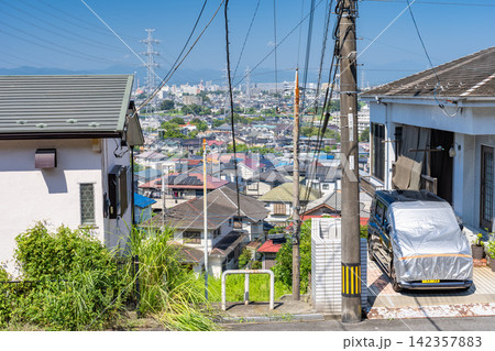 東京都日野市の高台から見下ろす広大な住宅街と送電鉄塔 142357883