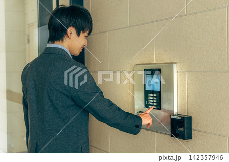 マンションのインターホンを押す男性 142357946