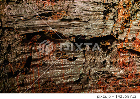 Cooled lava showing porous folds and iron-red mineral color, Raufarholshellir, Iceland 142358712