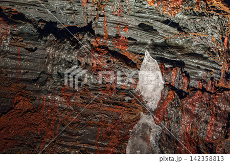 Cooled lava with small ice accents interrupting the rough surface, Raufarholshellir, Iceland 142358813