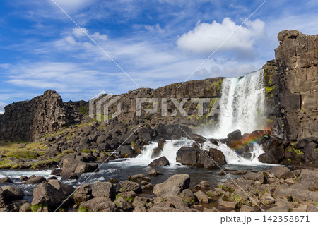 Direct morning sun reveals a natural rainbow through Oxararfoss spray at Thingvellir, Iceland 142358871