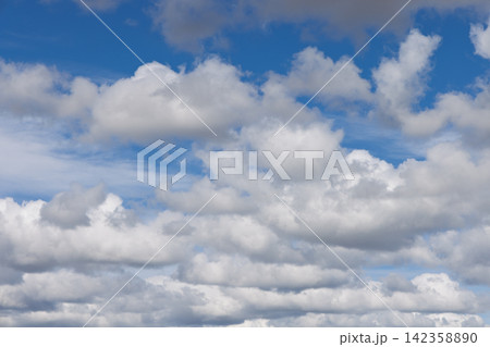 Layered white cumulus clouds in bright natural daylight against clear blue sky 142358890