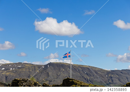 Icelandic flag waving above the park against a bright open horizon, Thingvellir, Iceland Icelandic flag waving above the park against a bright open horizon, Thingvellir, Iceland 142358893