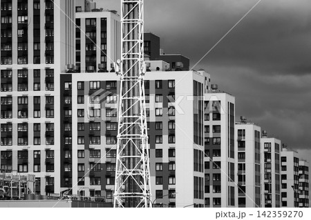 Black and white urban apartment buildings with construction crane and dramatic cloudy sky Black and white urban apartment buildings with construction crane and dramatic cloudy sky 142359270