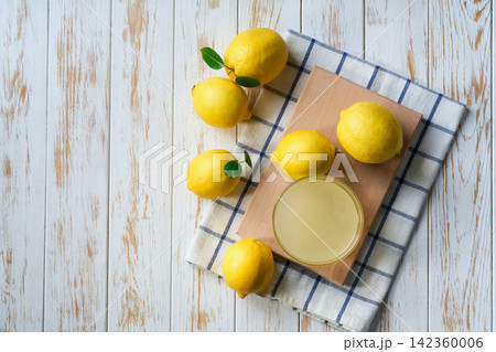 homemade lemon juice in glass and ripe lemons on white wooden table, with copy space for text. Top vie homemade lemon juice in glass and ripe lemons on white wooden table, with copy space for text. Top vie 142360006