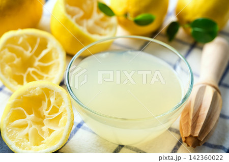 homemade lemon juice in small bowl on dark table, selective focus. freshly squeezed lemon juice . homemade lemon juice in small bowl on dark table, selective focus. freshly squeezed lemon juice . 142360022