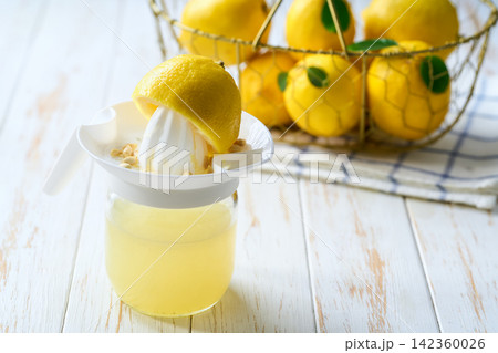 homemade lemon juice in bowl on white table with copy space for text. freshly squeezed lemon juice . 142360026
