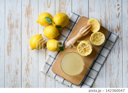 Making lemon juice from ripe lemons. Freshly squeezed lemon juice on a white table, top view. 142360047
