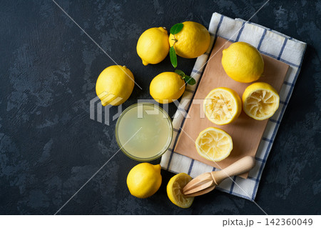 Freshly squeezed lemon juice on a dark table, top view. Making lemon juice from ripe lemons. 142360049