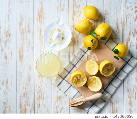 Making lemon juice from ripe lemons. Freshly squeezed lemon juice on a white table, top view. 142360050