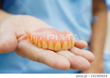 Asian senior woman patient holding teeth denture in her hand for chew food. 142360604