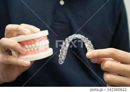 Man holding invisible aligner orthodontic retainer for dental teeth straightening. Man holding invisible aligner orthodontic retainer for dental teeth straightening. 142360622