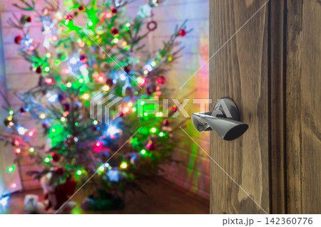 Opened wooden door to living room with Christmas tree. 142360776