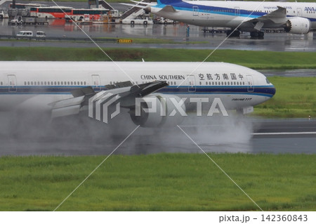 雨の滑走路に着陸する旅客機 エンジンの逆噴射の水煙 雨の滑走路に着陸する旅客機 エンジンの逆噴射の水煙 142360843