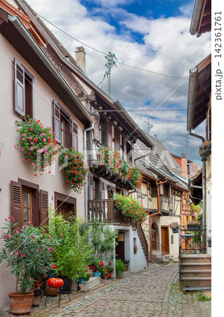 Picturesque historic street in Eguisheim Alsace France. Traditional half timbered houses and stone pavement under cloudy sky 142361761