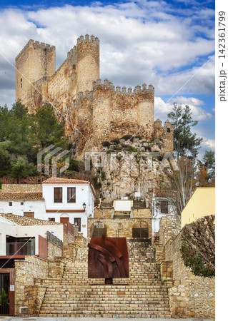 View of Almansa Castle from stone stairs in Albacete province, Spain. Medieval fortress architecture under cloudy sky in daytime View of Almansa Castle from stone stairs in Albacete province, Spain. Medieval fortress architecture under cloudy sky in daytime 142361799