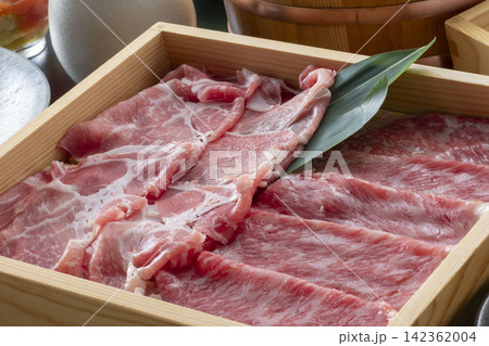 木製のしゃぶしゃぶ鍋に盛られた薄切り牛肉、青ねぎの装飾で彩る和食の美しい食卓 木製のしゃぶしゃぶ鍋に盛られた薄切り牛肉、青ねぎの装飾で彩る和食の美しい食卓 142362004