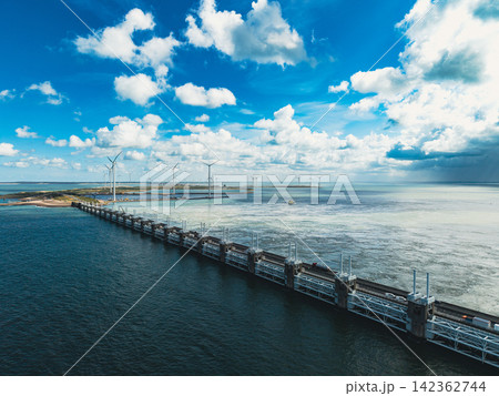 High angle wide horizontal aerial drone photograph of Eastern Scheldt storm surge barrier piers, sluice gates wind turbines and cloudy blue sky at Neeltje Jans Zeeland Netherlands on sunny summer day 142362744