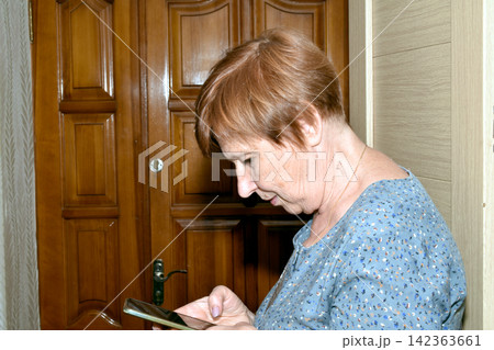The woman looks closely at the smartphone screen. The woman looks closely at the smartphone screen. 142363661