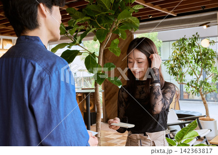 おしゃれなカフェで名刺交換をする若い男女のビジネスパーソン 142363817