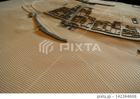 Detailed topographic terrain model displays raised landforms, and a planned settlement for geographic analysis and spatial planning. Concepts: cartography, urban development, geographic visualization. Detailed topographic terrain model displays raised landforms, and a planned settlement for geographic analysis and spatial planning. Concepts: cartography, urban development, geographic visualization. 142364608