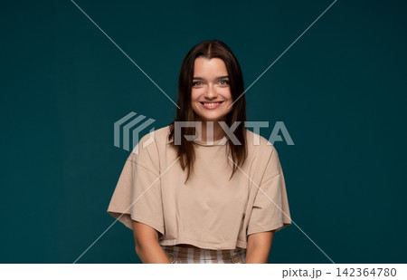 Young woman smiling with dark hair, wearing casual clothing, feeling youthful and expressing happiness and positivity Young woman smiling with dark hair, wearing casual clothing, feeling youthful and expressing happiness and positivity 142364780