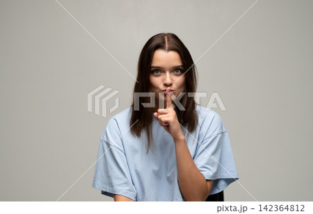 Woman making shhh gesture with finger on lips, indicating silence, secret, and confidential information Woman making shhh gesture with finger on lips, indicating silence, secret, and confidential information 142364812