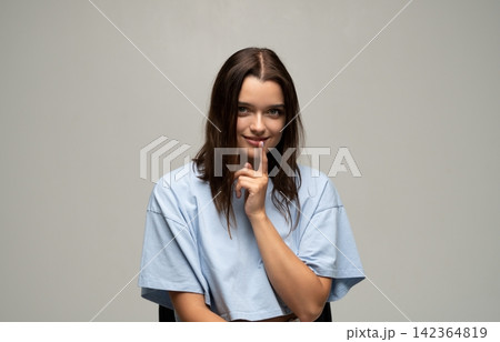 Young woman showing silence gesture, keeping a secret or mystery, asking for quiet, concept of privacy Young woman showing silence gesture, keeping a secret or mystery, asking for quiet, concept of privacy 142364819
