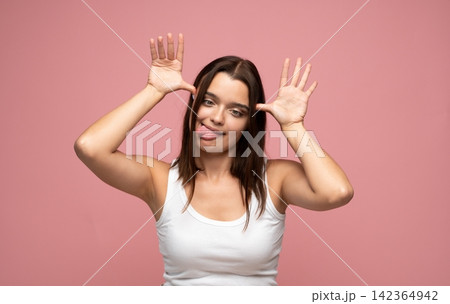Cheerful woman playfully making a goofy face, exuding joy and humor while having a great time Cheerful woman playfully making a goofy face, exuding joy and humor while having a great time 142364942
