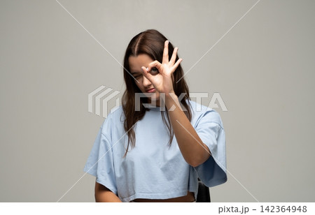 Young woman making okay hand gesture and winking, demonstrating approval, agreement, and excellence Young woman making okay hand gesture and winking, demonstrating approval, agreement, and excellence 142364948