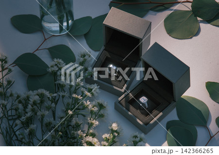 The wedding rings are in boxes on a corner of a white table, decorated with dried flowers 142366265
