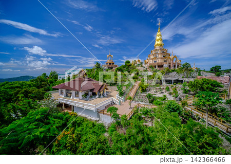 thai temple with golden pagoda and many building on the natural mountain surround by green forest at noon and blue clear sky in background thai temple with golden pagoda and many building on the natural mountain surround by green forest at noon and blue clear sky in background 142366466