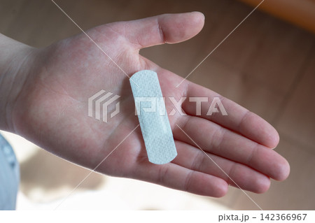 Young woman with medical adhesive plaster on the hand after vaccination. Fabric white bandage like first help for wound on the damage skin. Young woman with medical adhesive plaster on the hand after vaccination. Fabric white bandage like first help for wound on the damage skin. 142366967