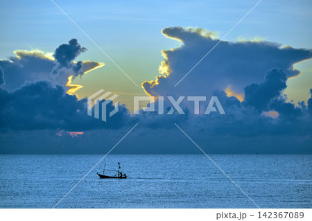morning sunshine with the cloudy sky over the sea with small silhouette fishing boat below 142367089