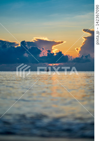 morning sunshine with the cloudy sky over the sea with small silhouette fishing boat below 142367090