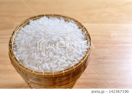 raw Thai's jasmine rice in Thai's traditional style bamboo's bowl on wooden dinner table 142367190